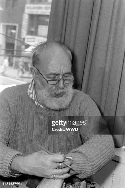Writer Edward Gorey answers questions during an interview while signing his books.