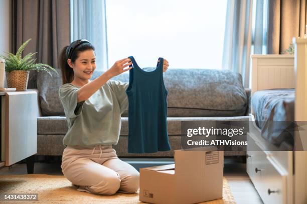 woman opening a shipment delivery and looking at the clothing purchased at home. - omnichannel retail stock pictures, royalty-free photos & images