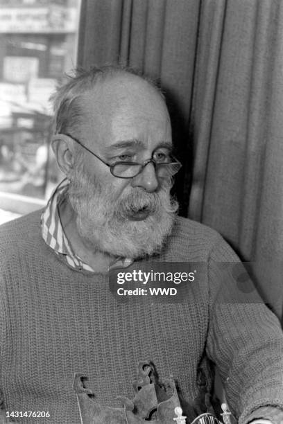 Writer Edward Gorey answers questions during an interview while signing his books.