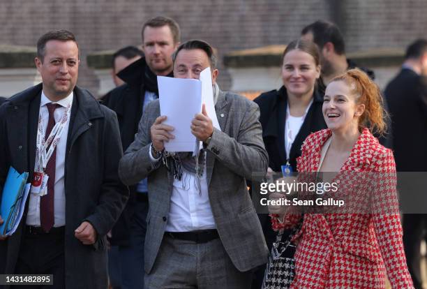 Luxembourg Prime Minister Xavier Bettel laughs and hides behind a document after he noticed photographers had seen him make a gesture while he had...