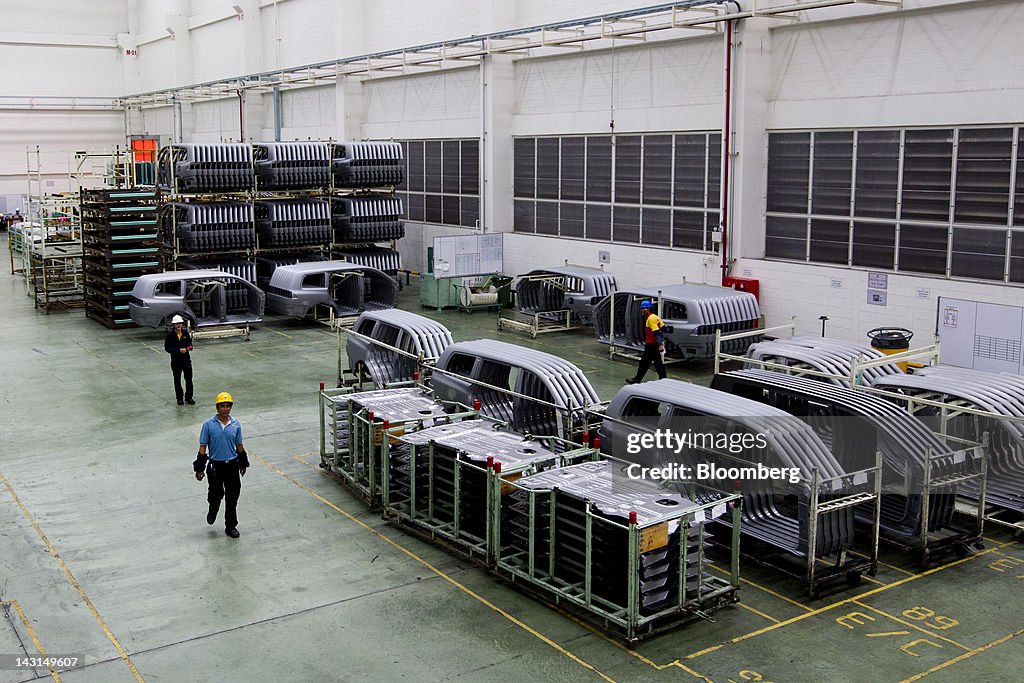 Workers walk past car parts inside Mitsubishi Motors Corp.'s factory ...
