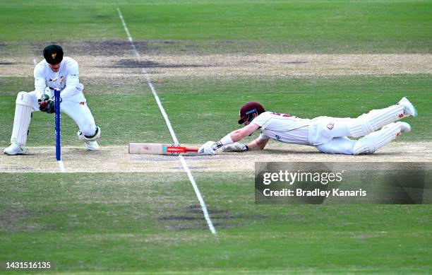 Jimmy Peirson of Queensland makes his ground as Tim Paine of Tasmania attempts to run him out during the Sheffield Shield match between Queensland...