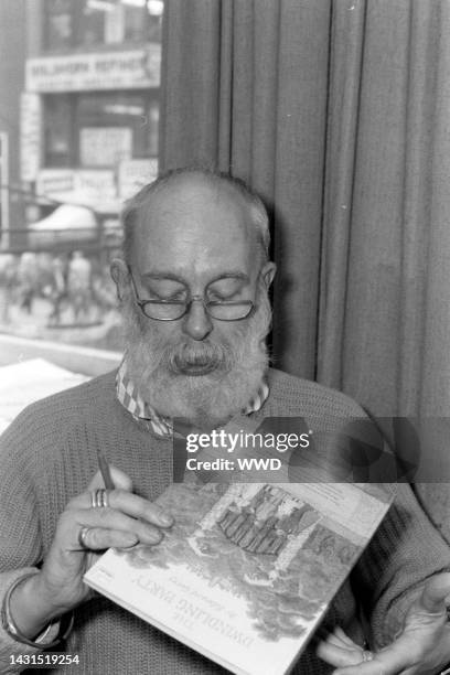 Writer Edward Gorey answers questions during an interview while signing his books.