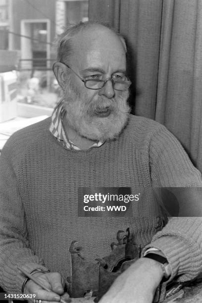 Writer Edward Gorey answers questions during an interview while signing his books.