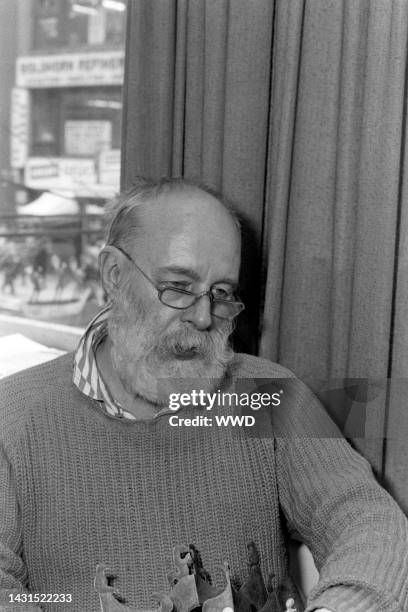 Writer Edward Gorey answers questions during an interview while signing his books.