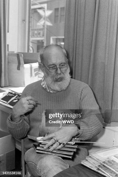 Writer Edward Gorey answers questions during an interview while signing his books.