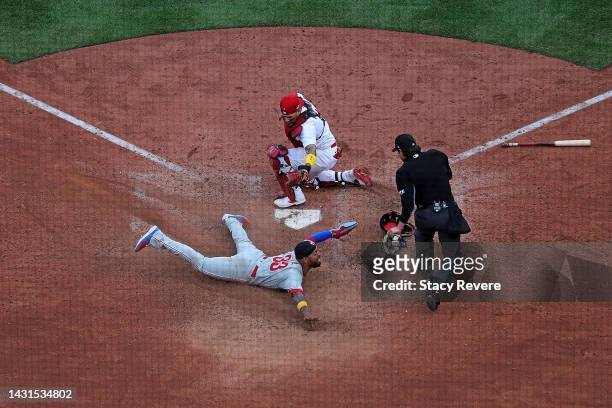 Edmundo Sosa of the Philadelphia Phillies beats a tag at home by Yadier Molina of the St. Louis Cardinals during the ninth inning of Game One of the...