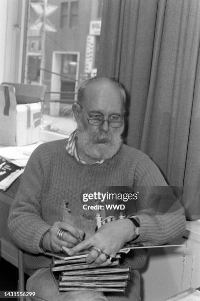 Writer Edward Gorey answers questions during an interview while signing his books.