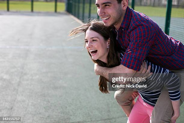 two friends having fun playing piggy backs - piggyback stock pictures, royalty-free photos & images