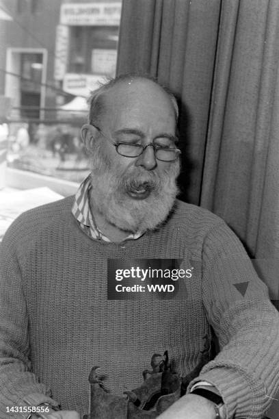 Writer Edward Gorey answers questions during an interview while signing his books.