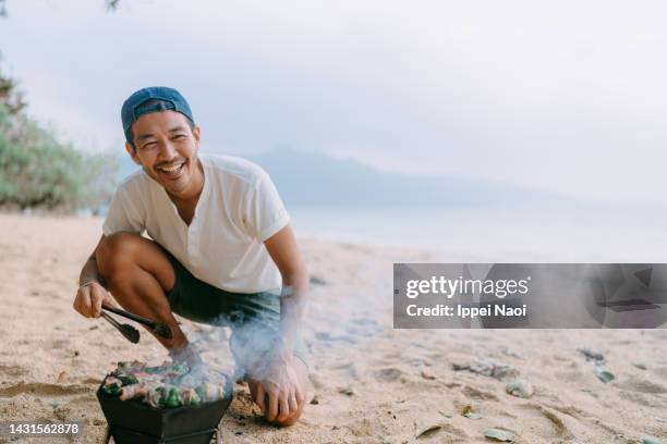 man enjoying bbq on beach - asian person bbq stock pictures, royalty-free photos & images