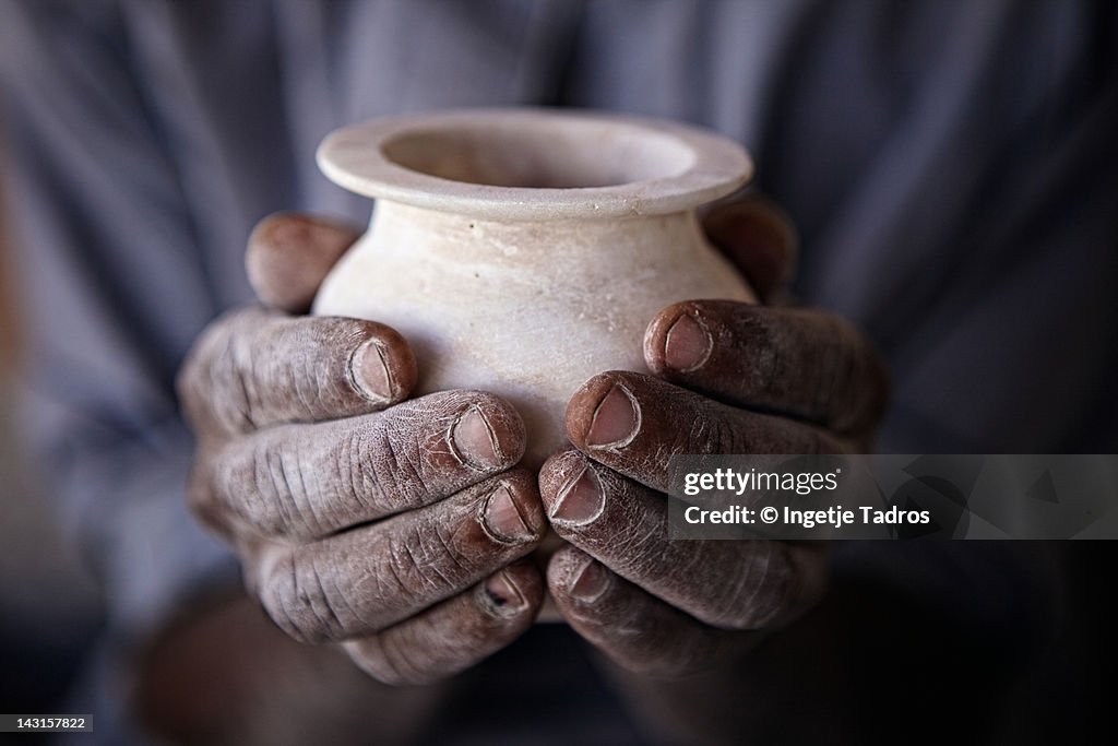 Two hands holdiong an Alabaster vase.