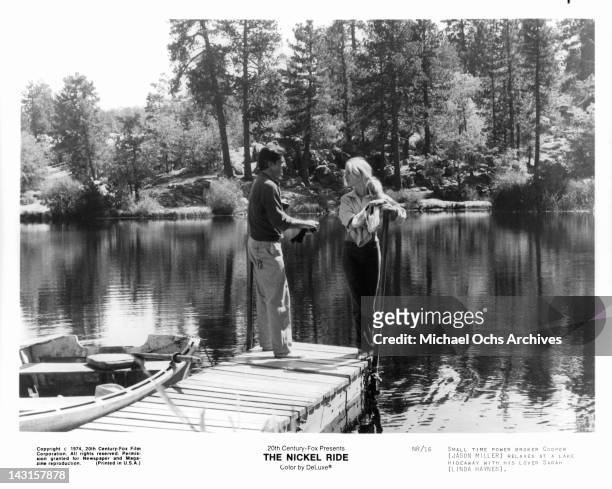 Jason Miller relaxes at lake hideaway with Linda Haynes in a scene from the film 'The Nickel Ride', 1974.