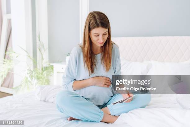 anticipation of future baby. pregnant woman gently holding ultrasound image result of a baby - baby touching belly fotografías e imágenes de stock