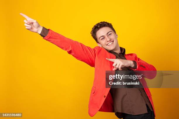 studio portrait of a cheerful white teenager boy in a pink jacket on a yellow background - handsome stock pictures, royalty-free photos & images