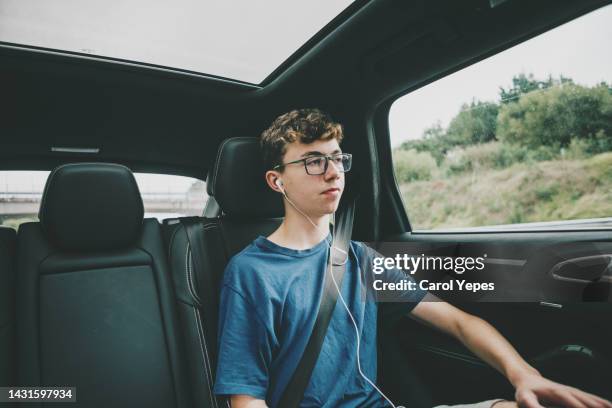 teenager sitting on the back of the car while listening to music - teenage boy looking out window stock pictures, royalty-free photos & images