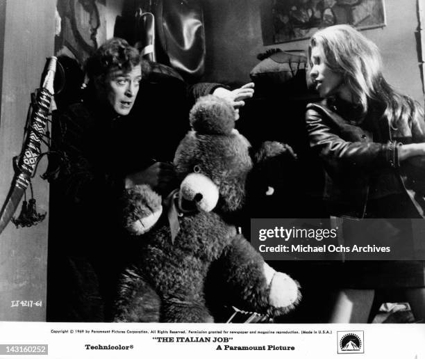 Michael Caine holding giant teddy bear as Margaret Blye takes a swing at him in a scene from the film 'The Italian Job', 1969.