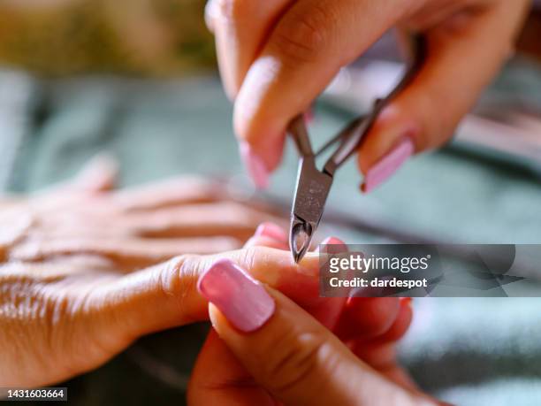 closeup shot of a woman using a cuticle clipper to give a nail manicure. - nagelklippare bildbanksfoton och bilder