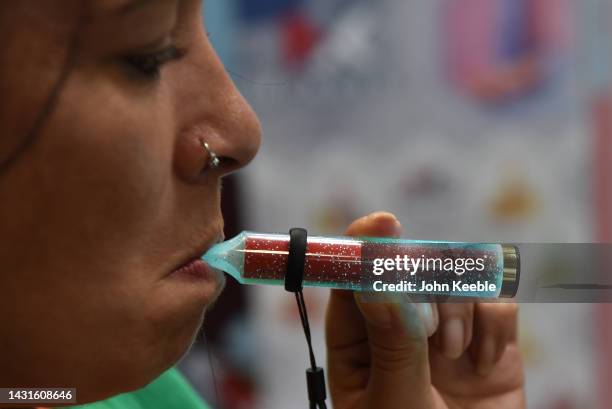 An exhibitor vapes on a McKesse light up/glowing disposable vape, e-cigarette during the Vaper Expo at National Exhibition Centre on October 07, 2022...