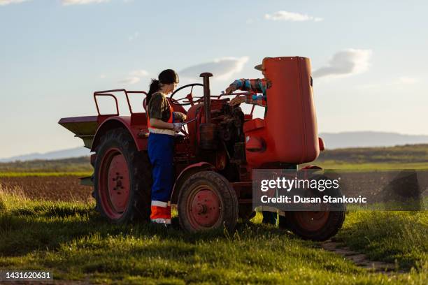 a young woman and a senior man repairing the tractor - tractor repair stock pictures, royalty-free photos & images