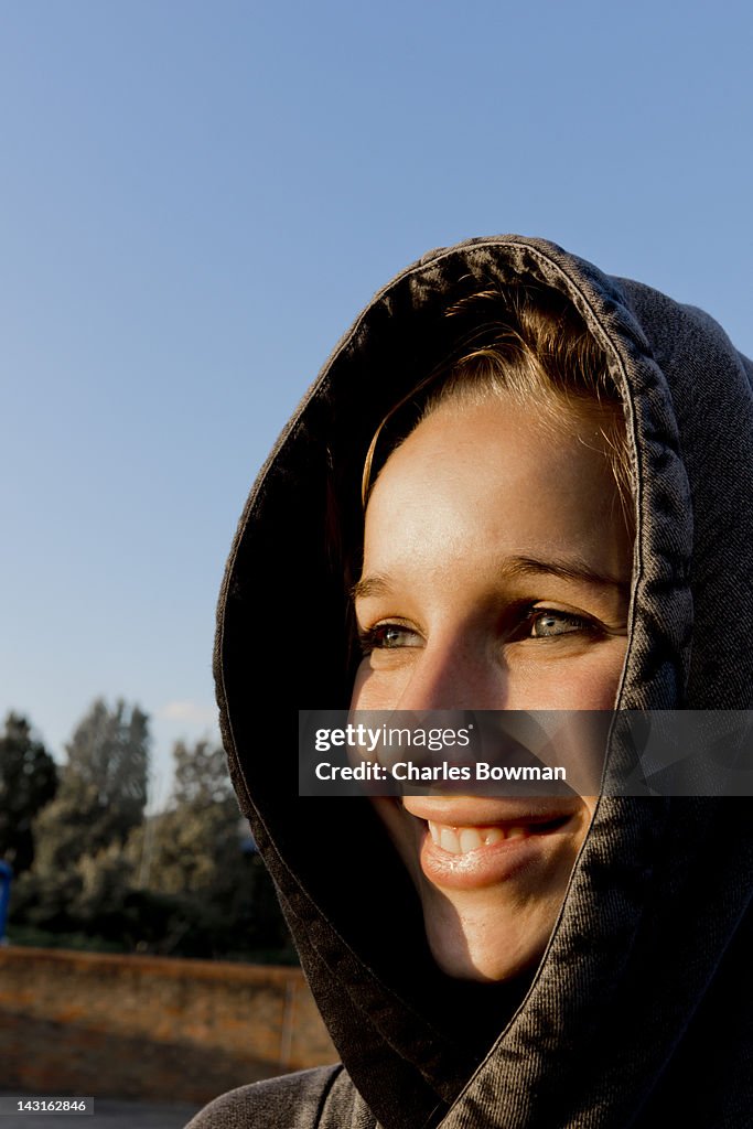 Teenager in hoodie smiles brilliantly.