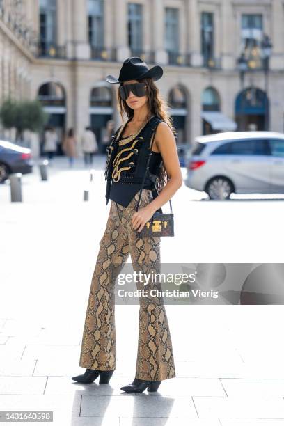 Sabina Jakubowicz wears cowboy hat, vest, bag, sunglasses, pants with snake print Louis Vuitton outside Louis Vuitton during Paris Fashion Week -...