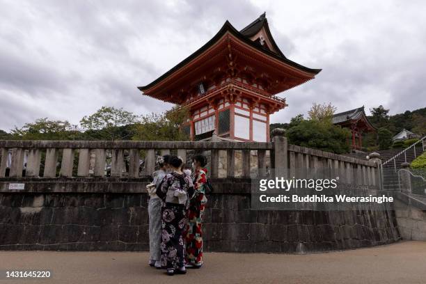 Tourists dressed in traditional Japanese outfits talk in front of the Kiyomizu Temple, one of Japan's most popular tourist destinations on October...