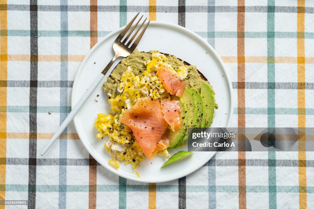 Breakfast with bread, scrambled eggs, salmon, avocado