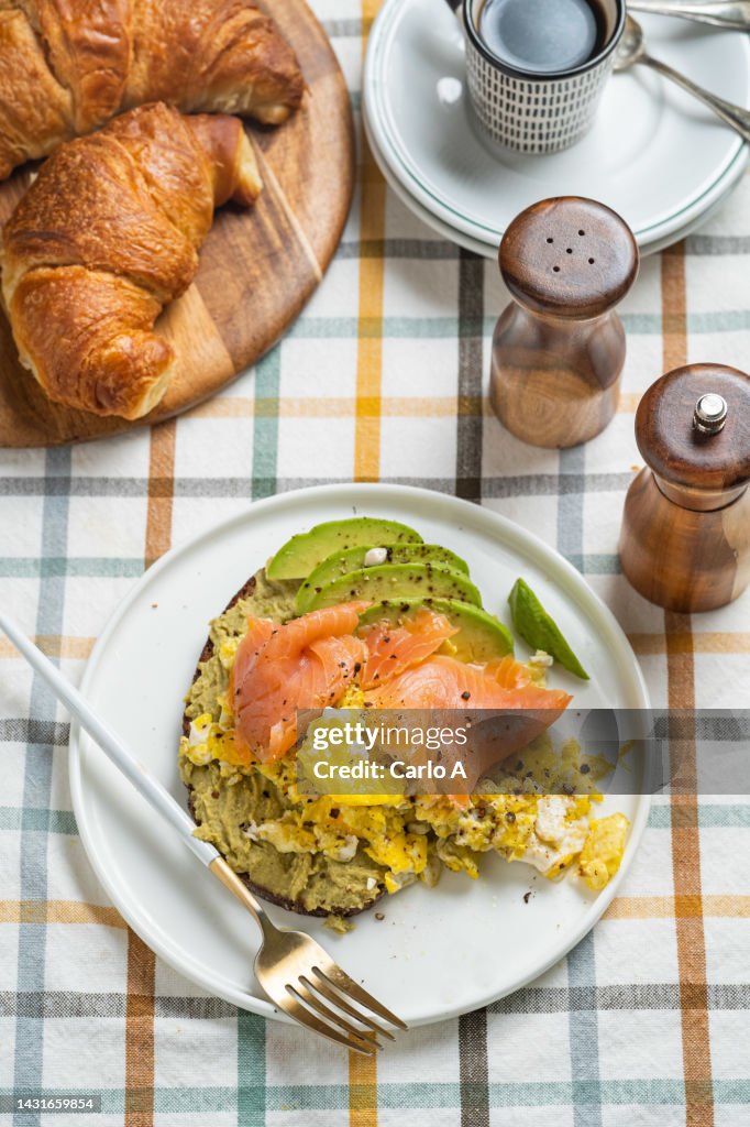 Breakfast with bread, scrambled eggs, salmon, avocado