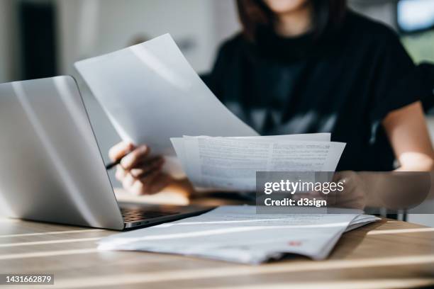 cropped shot of young asian woman handling personal banking and finance with laptop at home. planning budget and calculating expenses. managing taxes and financial bills. wealth management. digital banking habits. smart banking with technology - documents fotografías e imágenes de stock