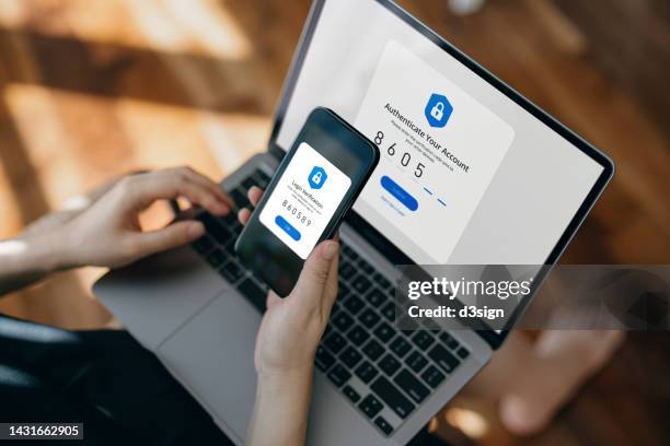 cropped hand of woman using mobile device with two-factor authentication (2fa) security while logging in securely to her laptop. privacy protection, internet and mobile security - security stock-fotos und bilder