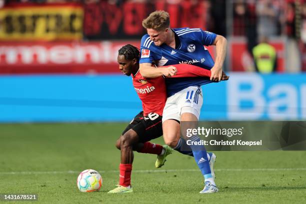 Jeremie Frimpong of Bayer 04 Leverkusen is challenged by Marius Buelter of FC Schalke 04 during the Bundesliga match between Bayer 04 Leverkusen and...