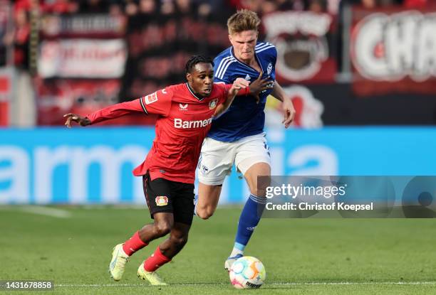 Jeremie Frimpong of Bayer 04 Leverkusen is challenged by Marius Buelter of FC Schalke 04 during the Bundesliga match between Bayer 04 Leverkusen and...