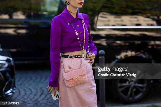 Guest wears purple button up top, belt with logo print, pink bag, high waisted skirt outside Chanel during Paris Fashion Week - Womenswear...