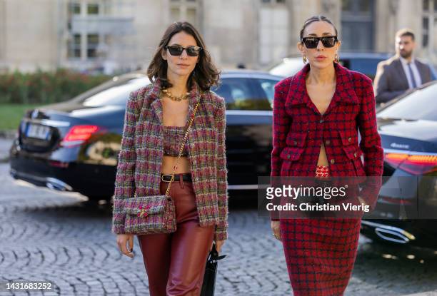 Guest wears blazer, cropped top, bag, red leather pants & a guest wears red black checkered jacket, micro bag, skirt, black boots outside Chanel...