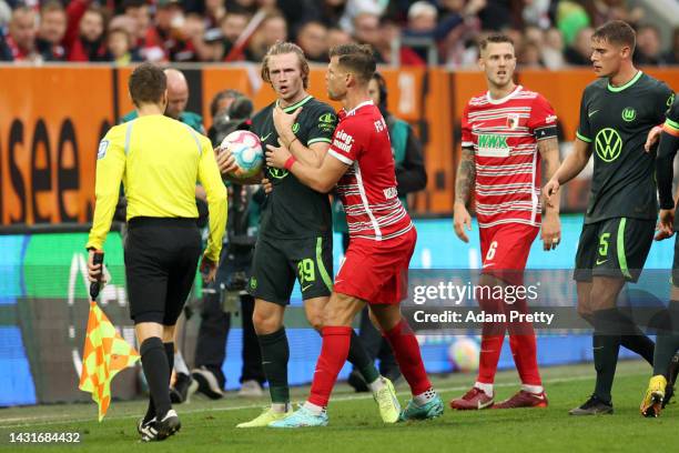 Patrick Wimmer of VfL Wolfsburg gestures as Referee Daniel Siebert shows multiple yellow cards during the Bundesliga match between FC Augsburg and...