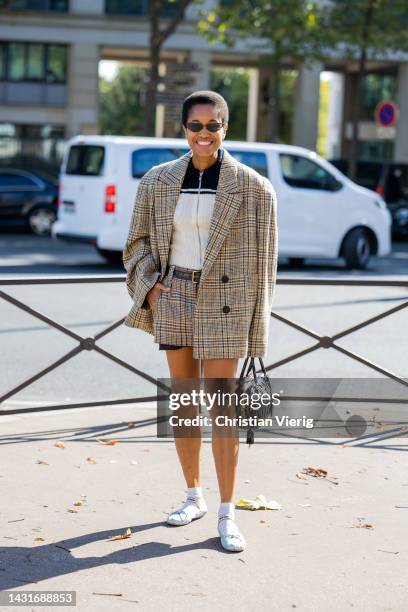 Tamu McPherson wears oversized beige blazer, shorts, black bag outside Miu Miu during Paris Fashion Week - Womenswear Spring/Summer 2023 : Day Nine...