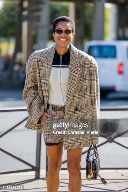 Tamu McPherson wears oversized beige blazer, shorts, black bag outside Miu Miu during Paris Fashion Week - Womenswear Spring/Summer 2023 : Day Nine...