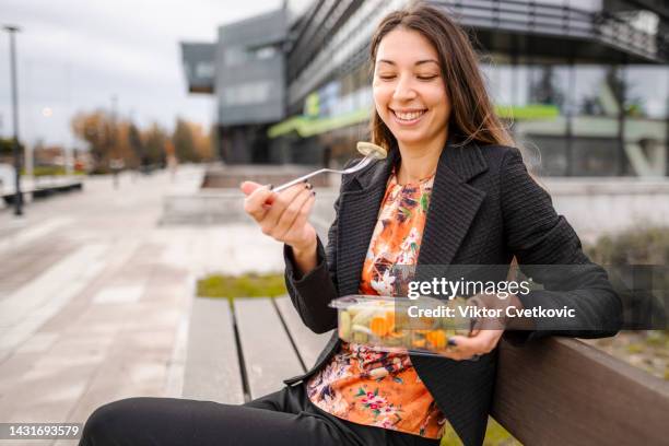 young businesswoman on a lunch break from work in the park near office building - lunch break stock pictures, royalty-free photos & images
