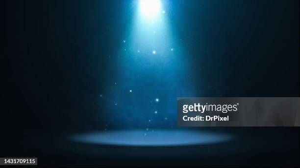 blue spotlight with particles illuminating the stage - blue sparkle background photos et images de collection