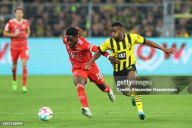 Alphonso Davies of Bayern Munich is challenged by Youssoufa Moukoko of Borussia Dortmund during the Bundesliga match between Borussia Dortmund and FC...