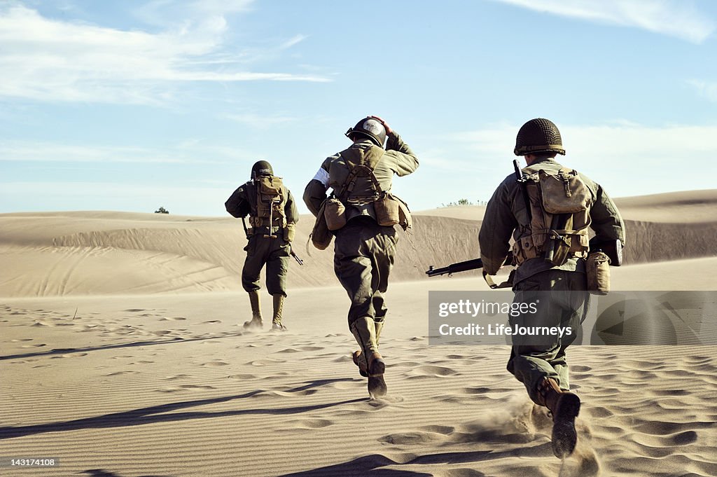 Three WWII Soldiers Running In The Desert Sand