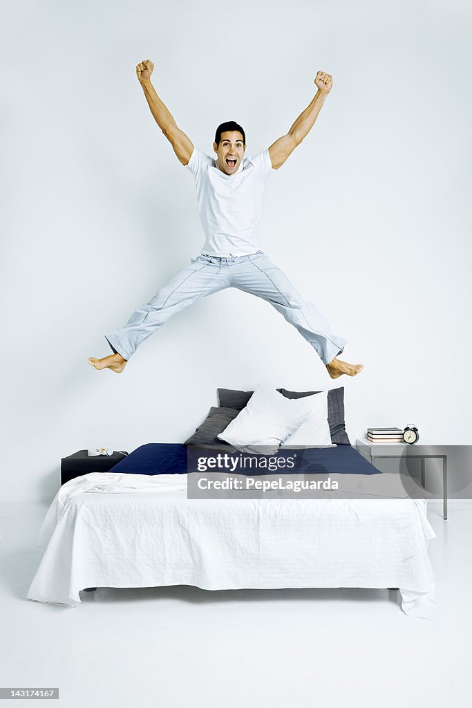 Winning man jumping on bed