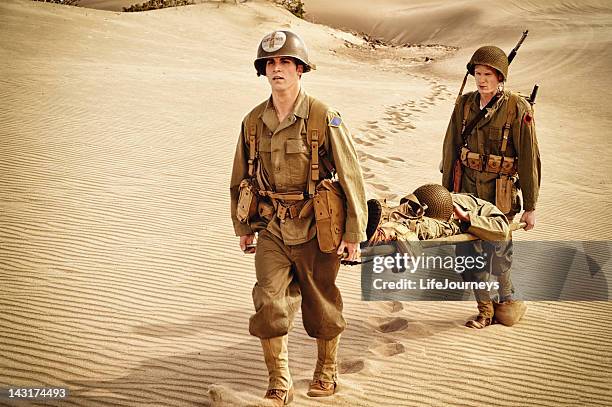 wwii medic and soldier evacuating wounded man on litter - wounded vet stock pictures, royalty-free photos & images