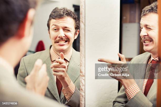 man looking at reflection in mirror - mirror stockfoto's en -beelden