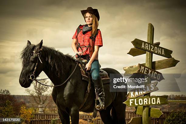 cowgirl auf schwarze pferd im road sign - woman horse stock-fotos und bilder