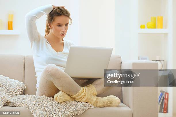 beautiful, young,  thoughtful, blond woman using laptop at home - strumpbyxor bildbanksfoton och bilder