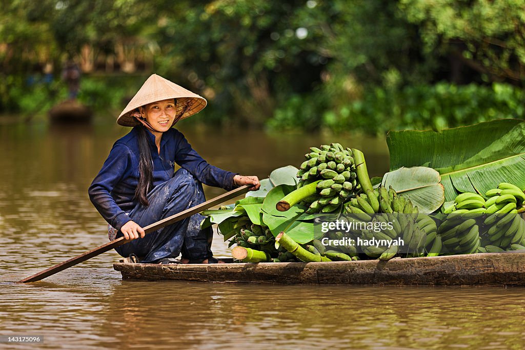 Vietnamese woman rowing boat in the Mekong River Delta, Vietnam