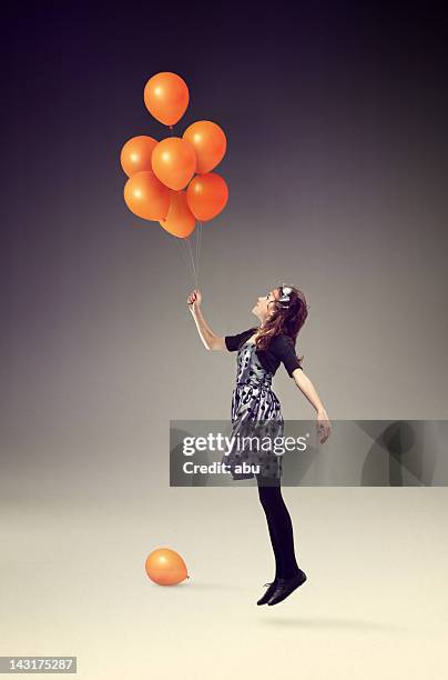 up in the air with orange balloons - balloon girl stock pictures, royalty-free photos & images