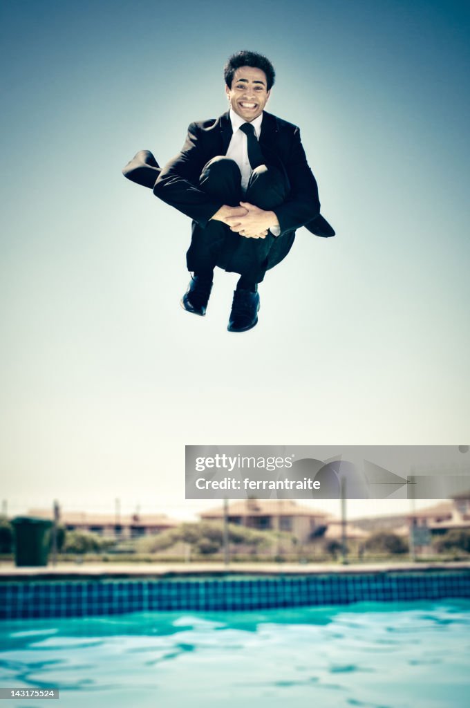 Businessman jumping in the pool